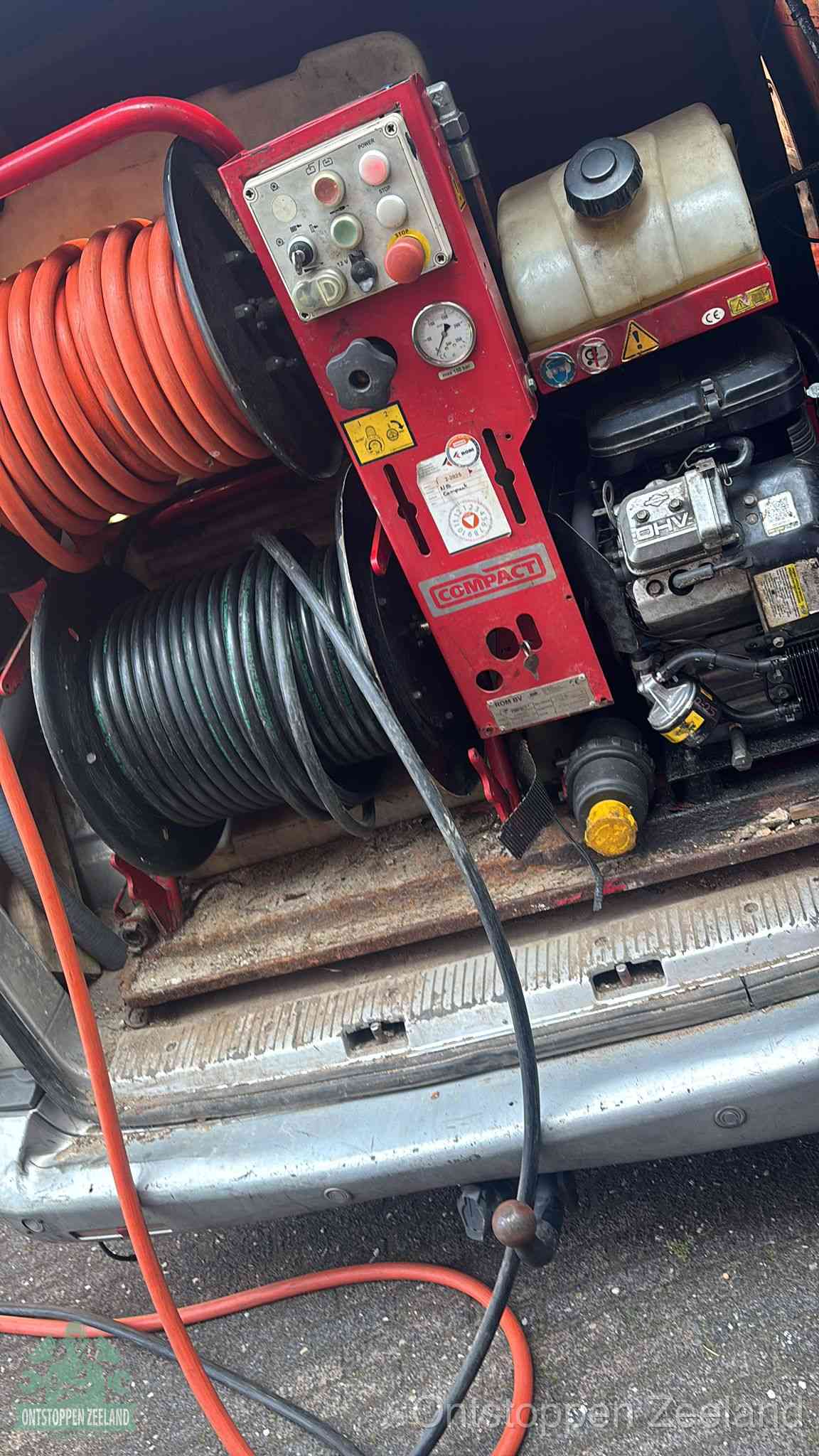 Een rood hogedruk-rioolreinigingstoestel in de laadbak van de bedrijfsbus, apparatuur voor een hardnekkige afvoerverstopping in Zeeland