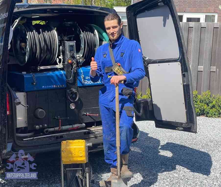Een monteur bij de werkbus met grote hogedruk-slanghaspels, apparatuur voor hardnekkige afvoerverstoppingen in Zeeland