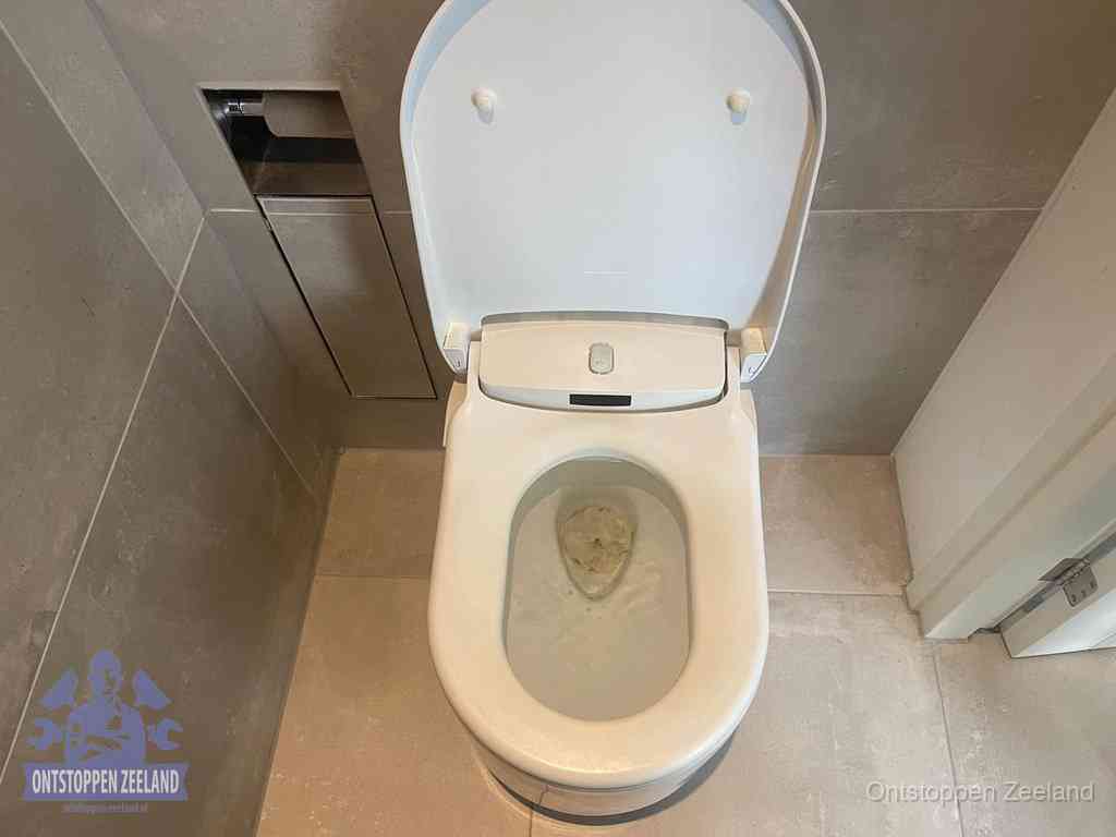 Een wit hangtoilet waarin een prop wc-papier op het water blijft drijven, een duidelijk signaal van een verstopte wc in Zeeland