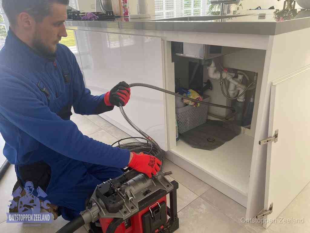 Een monteur reinigt de keukenafvoer grondig met een veermachine om terugkerende gootsteenverstoppingen te voorkomen in Zeeland